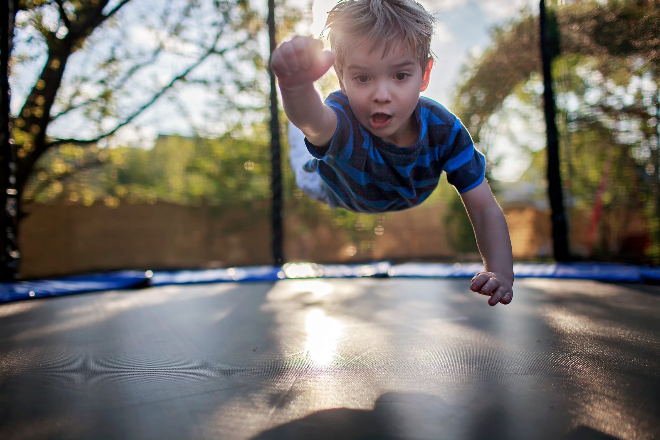 Little Boy Jumping on the Trampoline like a Superhero